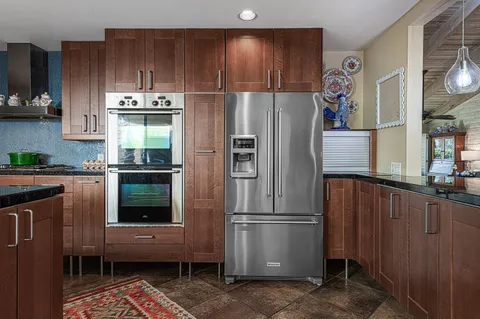 a kitchen with stainless steel appliances granite countertop a refrigerator a sink and wooden cabinets