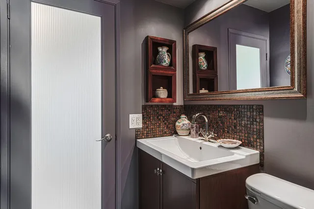 a bedroom with a bed a computer on the desk and a dresser next to a window