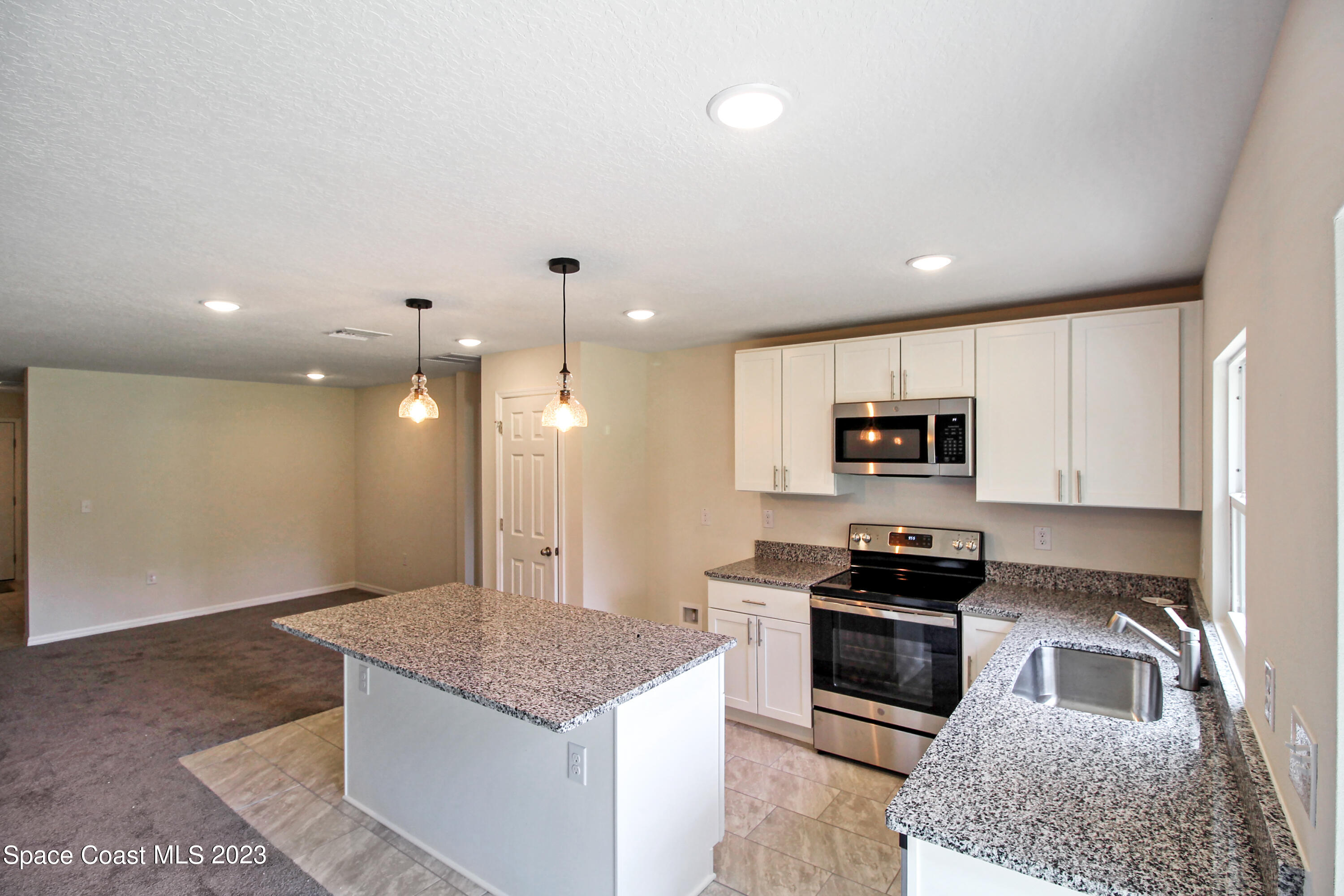 751 Schean Avenue Southwest Palm Bay, FL 32908 - Photo 2 of 12 a kitchen with stainless steel appliances kitchen island granite countertop a stove a sink and a microwave