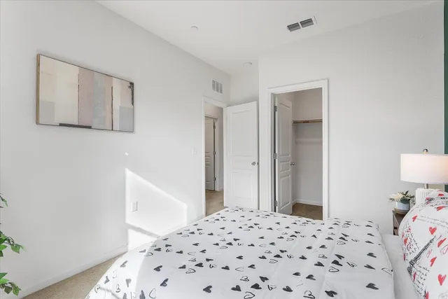 a bedroom with a bed and a lamp on dresser