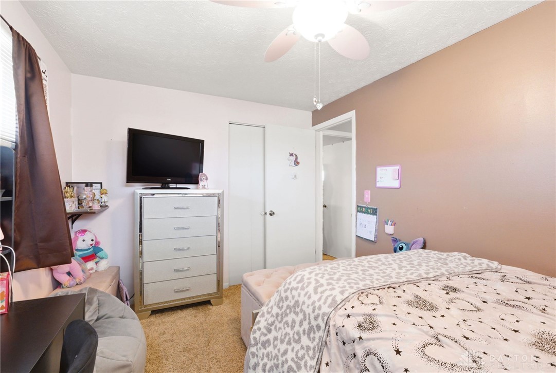 5171 Fishburg Road Dayton, OH 45424 - Photo 24 of 35 This cozy bedroom features a ceiling fan, a large window, and carpet flooring.