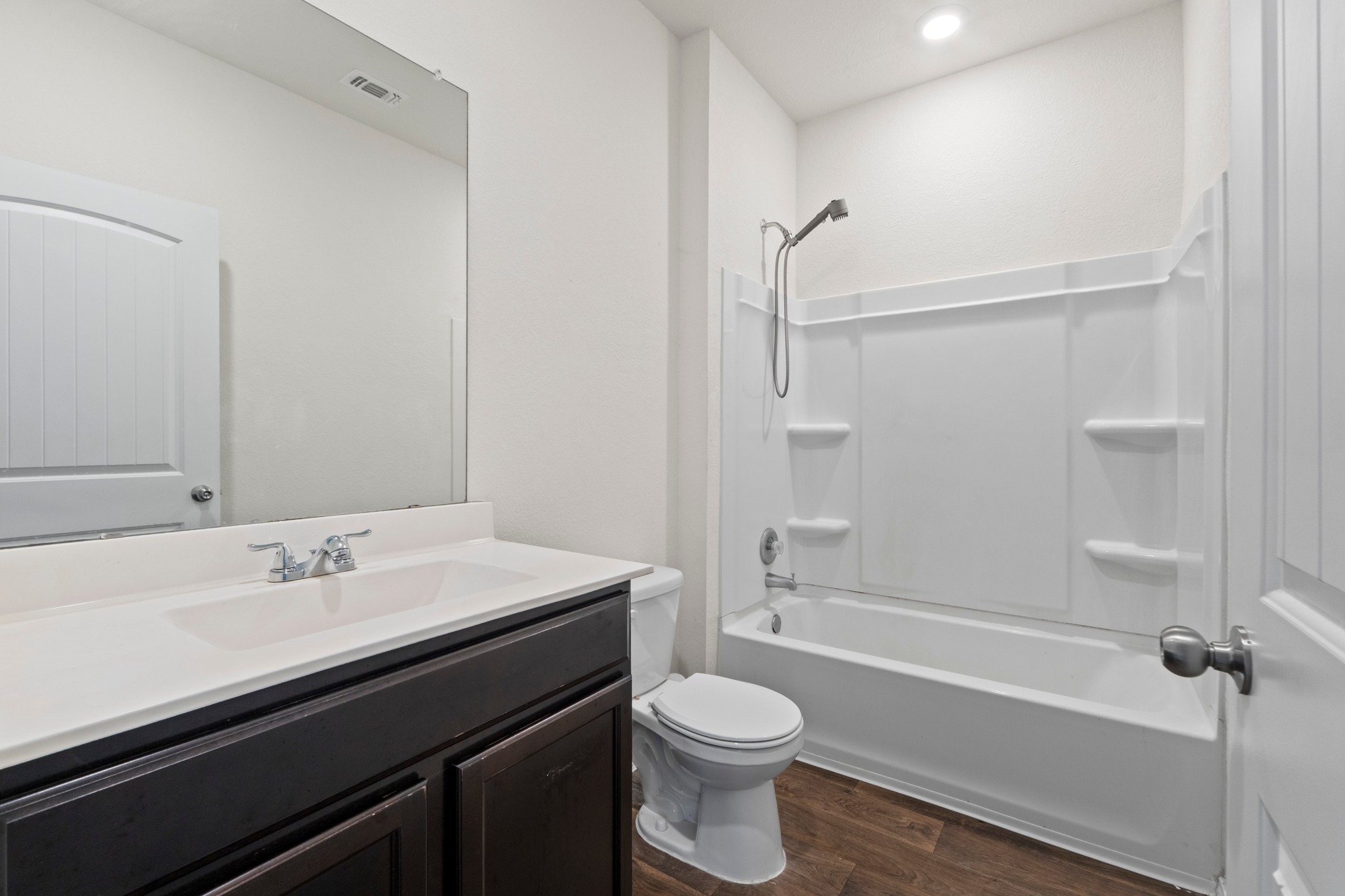 14917 Bajada Rd Manor Manor, TX 78653 - Photo 15 of 31 Modern bathroom featuring a dark wood-finish vanity with a white countertop and integrated sink, chrome faucet, and a large wall-mounted mirror