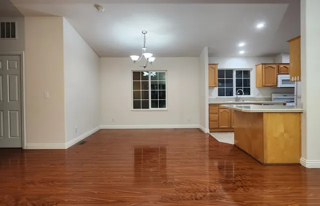 an empty room with wooden floor and chandelier