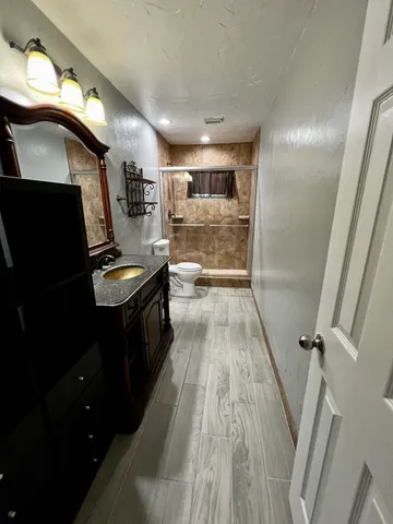 a kitchen with granite countertop a refrigerator a sink and wooden floor