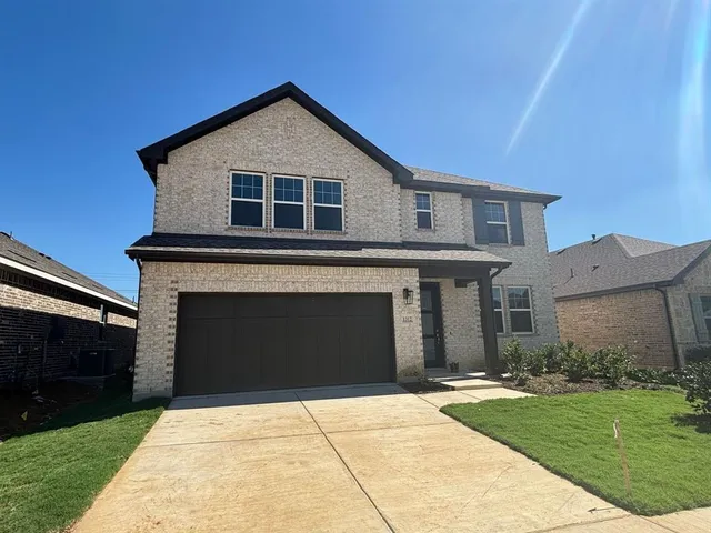 a front view of a house with yard and parking