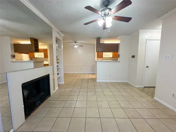 a view of an empty room with a fireplace and a chandelier fan