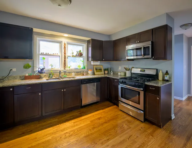 a kitchen with stainless steel appliances kitchen island granite countertop a sink stove and microwave