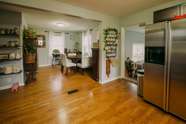 a living room with stainless steel appliances furniture windows and a wooden floor