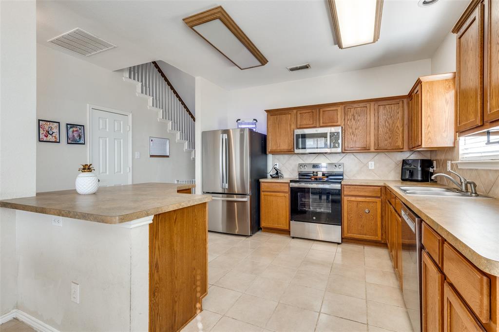 301 Turquoise Drive Fort Worth, TX 76131 - Photo 19 of 33 a kitchen with stainless steel appliances granite countertop a sink stove refrigerator and a microwave oven