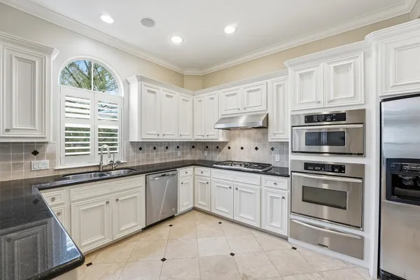 a kitchen with granite countertop white cabinets and stainless steel appliances