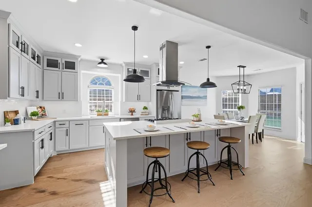 a kitchen with stainless steel appliances a dining table chairs and white cabinets