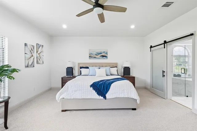 a spacious bedroom with a bed a couch and a chandelier