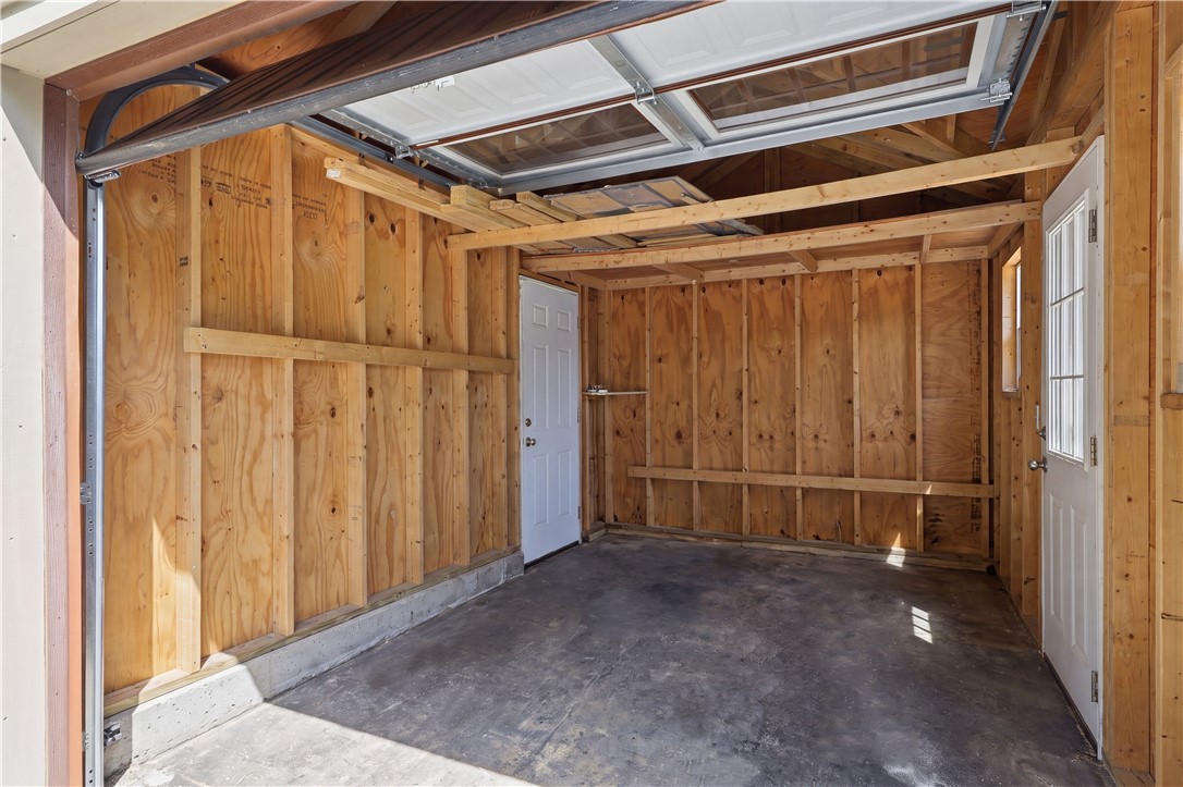 2057 Stirnie Road Victor, NY 14564 - Photo 38 of 48 Another view of the secondary entrance to the attached 3 car garage, reveals a highly practical secondary storage bay or workshop stall. Complete with an automatic overhead garage door, concrete flooring, dual pedestrian entry doors, and exposed wood stud framing, it provides the space for a single vehicle, ATVs, workshop projects, or yard equipment storage.