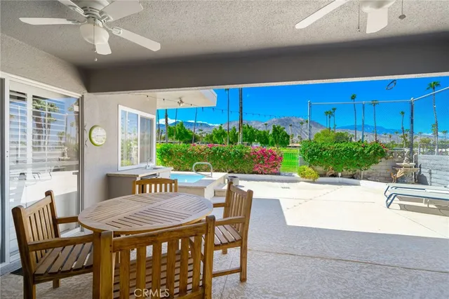 a view of a patio with table and chairs potted plants and a floor to ceiling window