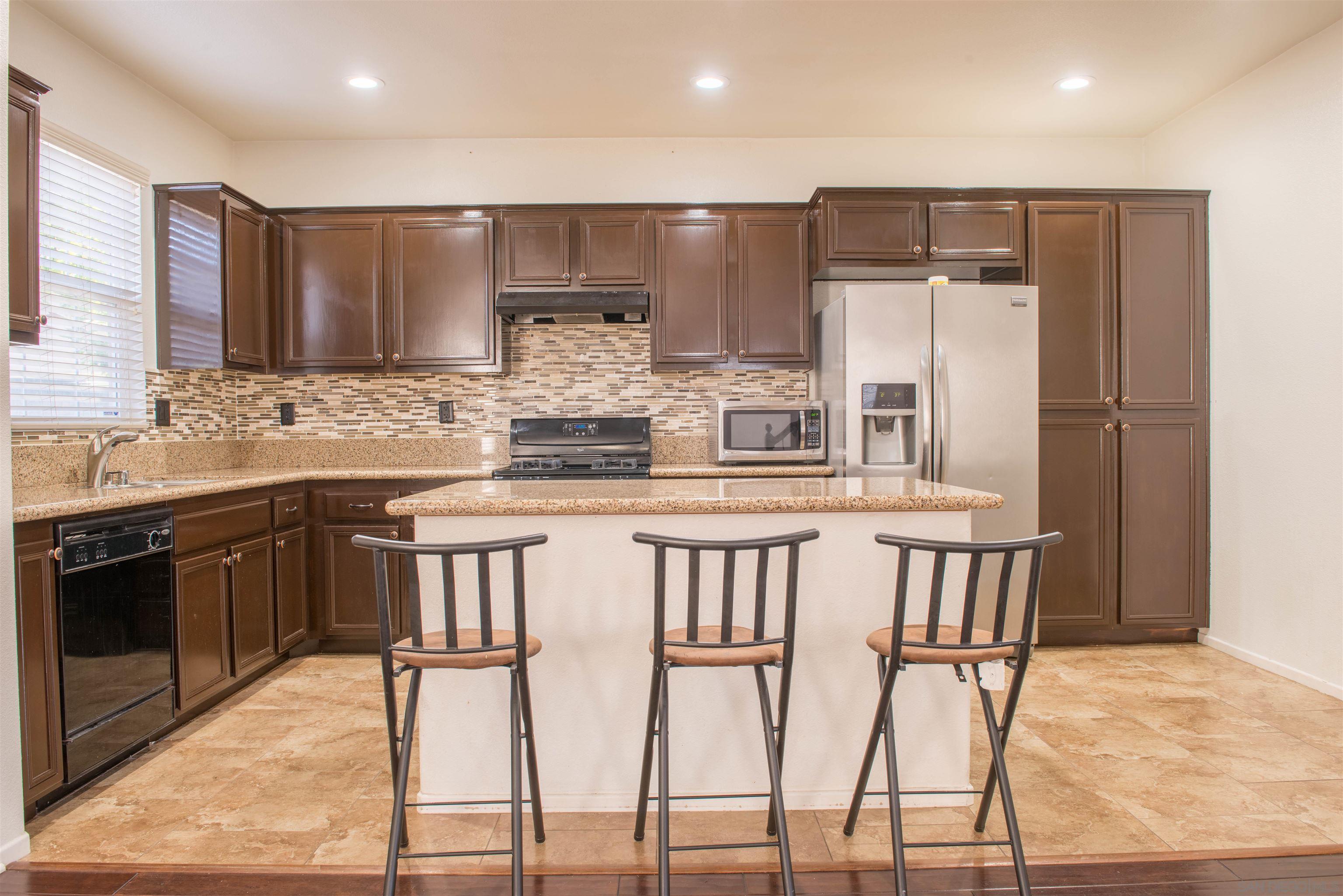 a kitchen with kitchen island granite countertop a stove a sink and a refrigerator