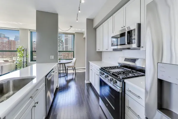 a kitchen with stainless steel appliances a stove cabinets and a wooden floor