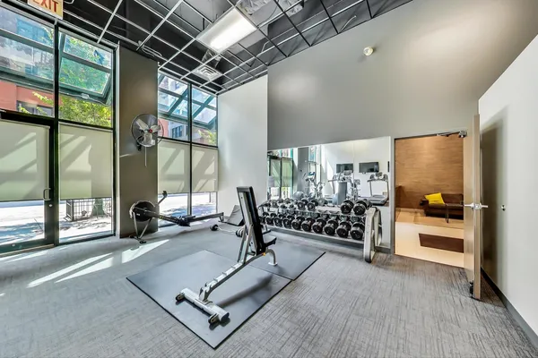 a living room with furniture gym equipment and a large window