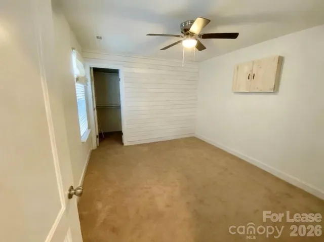 an empty room with a ceiling fan and a window