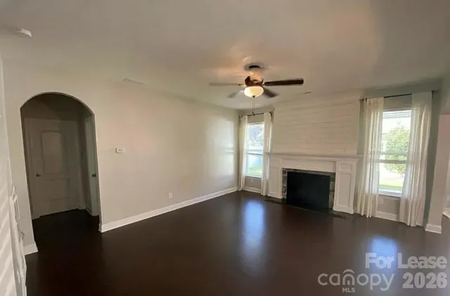 an empty room with windows fireplace and wooden floor
