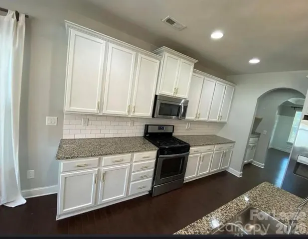 a kitchen with stainless steel appliances granite countertop a stove a sink and a microwave