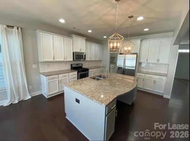 a kitchen with kitchen island granite countertop a sink a counter space appliances and cabinets