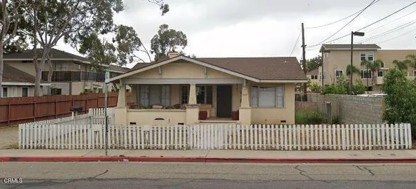a view of a house with a small yard and wooden fence