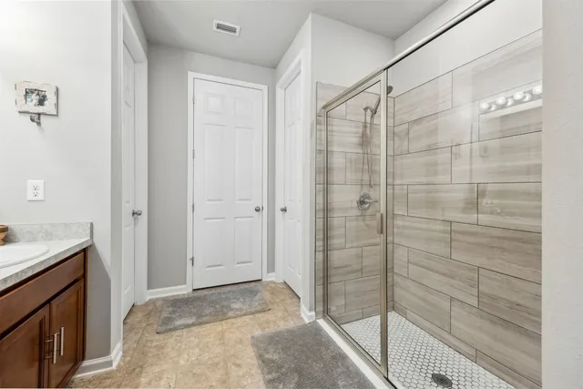 a spacious bathroom with a double vanity sink a large mirror and a shower