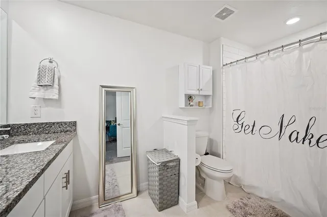 a bathroom with a granite countertop sink toilet and shower