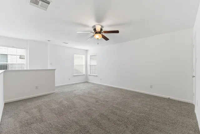 an empty room with a window and a ceiling fan