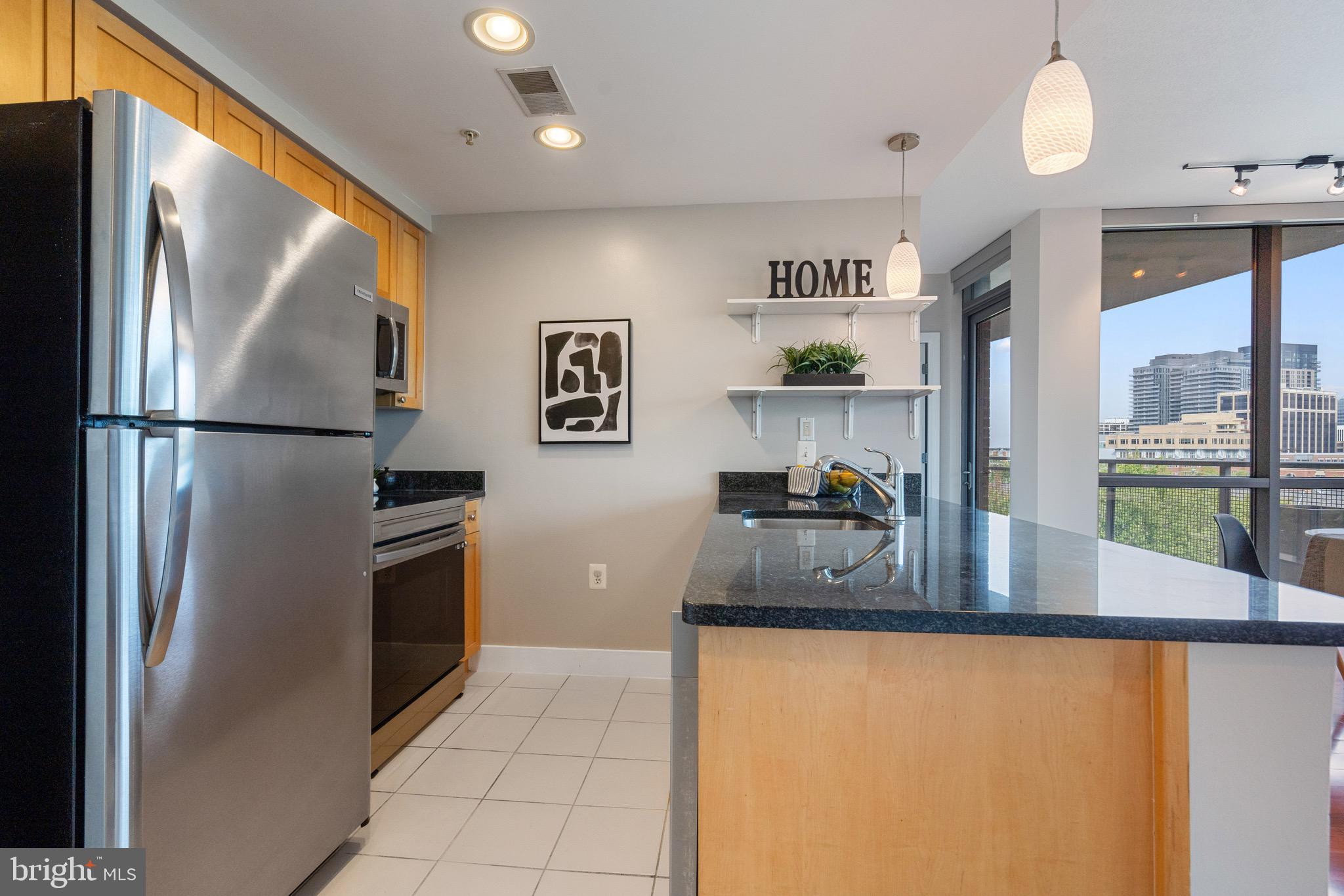 2001 15th Street North, Unit 306 Arlington, VA 22201 - Photo 13 of 56 a kitchen with stainless steel appliances granite countertop a refrigerator a stove and a sink with wooden floor