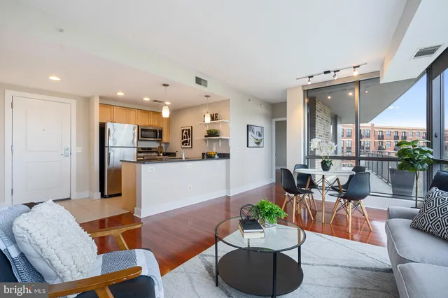 a kitchen with stainless steel appliances kitchen island granite countertop a dining table chairs and a refrigerator