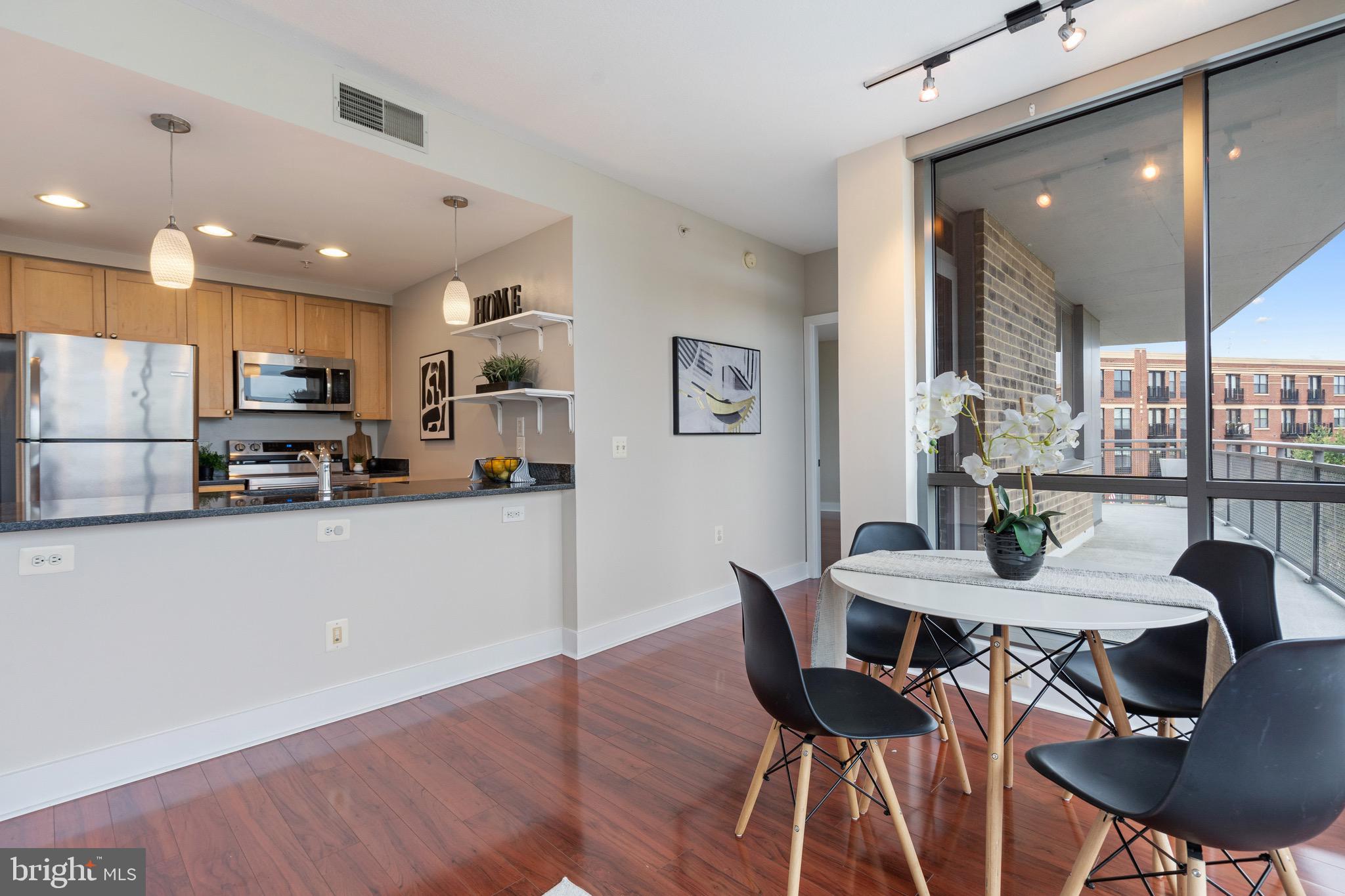 2001 15th Street North, Unit 306 Arlington, VA 22201 - Photo 19 of 56 a kitchen with stainless steel appliances kitchen island granite countertop a dining table chairs and a refrigerator