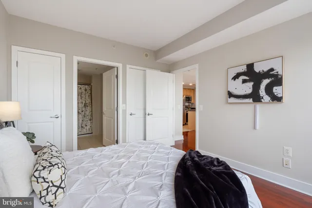 a bedroom with a bed a table and wooden floor