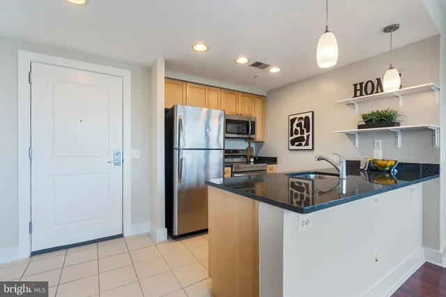 a living room with stainless steel appliances granite countertop a couch a table and chairs in it