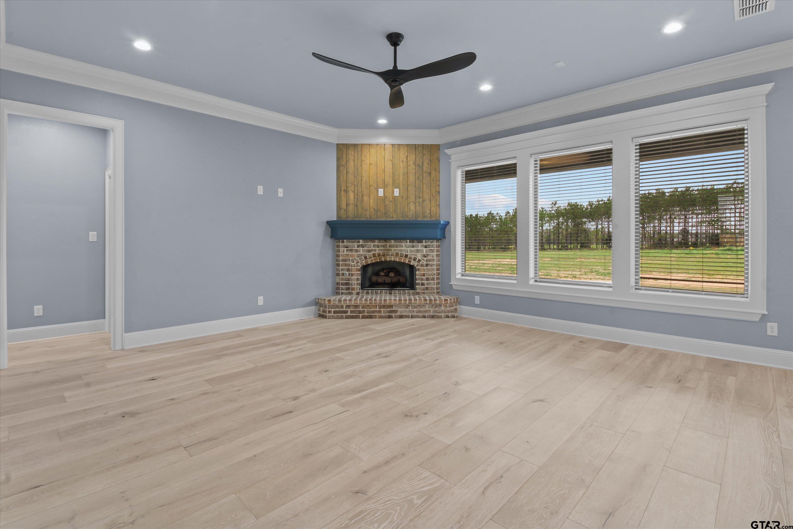 11236 Bryce Circle Flint, TX 75762 - Photo 11 of 44 an empty room with fireplace wooden floor a ceiling fan and a rug