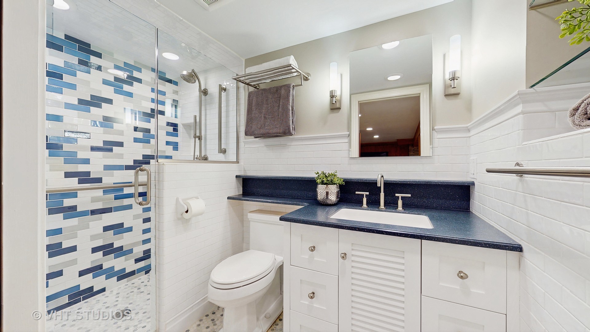 1321 Sheridan Road Wilmette, IL 60091 - Photo 28 of 36 a bathroom with a granite countertop sink toilet mirror and shower