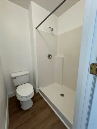 a bathroom with a granite countertop toilet a sink a mirror and a shower