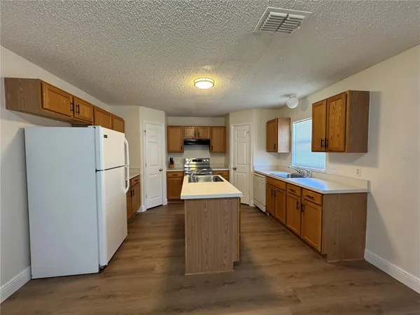 a large kitchen with stainless steel appliances a refrigerator a stove top oven a sink dishwasher and wooden cabinets