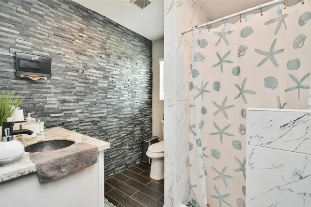 a bathroom with a granite countertop sink a mirror and a shower