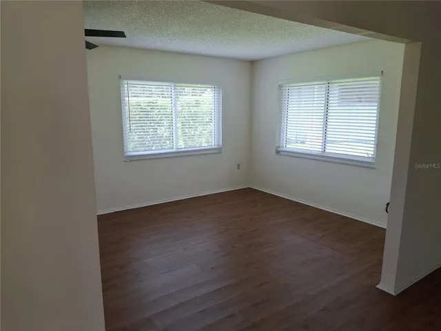 a view of an empty room with a window and wooden floor