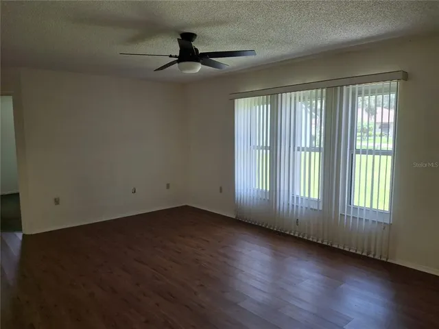 a view of an empty room with wooden floor and windows