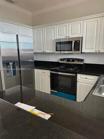 a kitchen with stainless steel appliances granite countertop a stove a microwave and a refrigerator