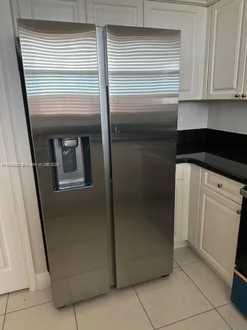 a kitchen with a refrigerator and white cabinets