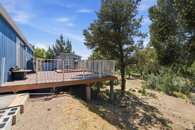 327 North Lodge Road Central, UT 84722 - Photo 25 of 45 Elevated wood-finish deck featuring white railings, a blue exterior, and surrounding mature trees