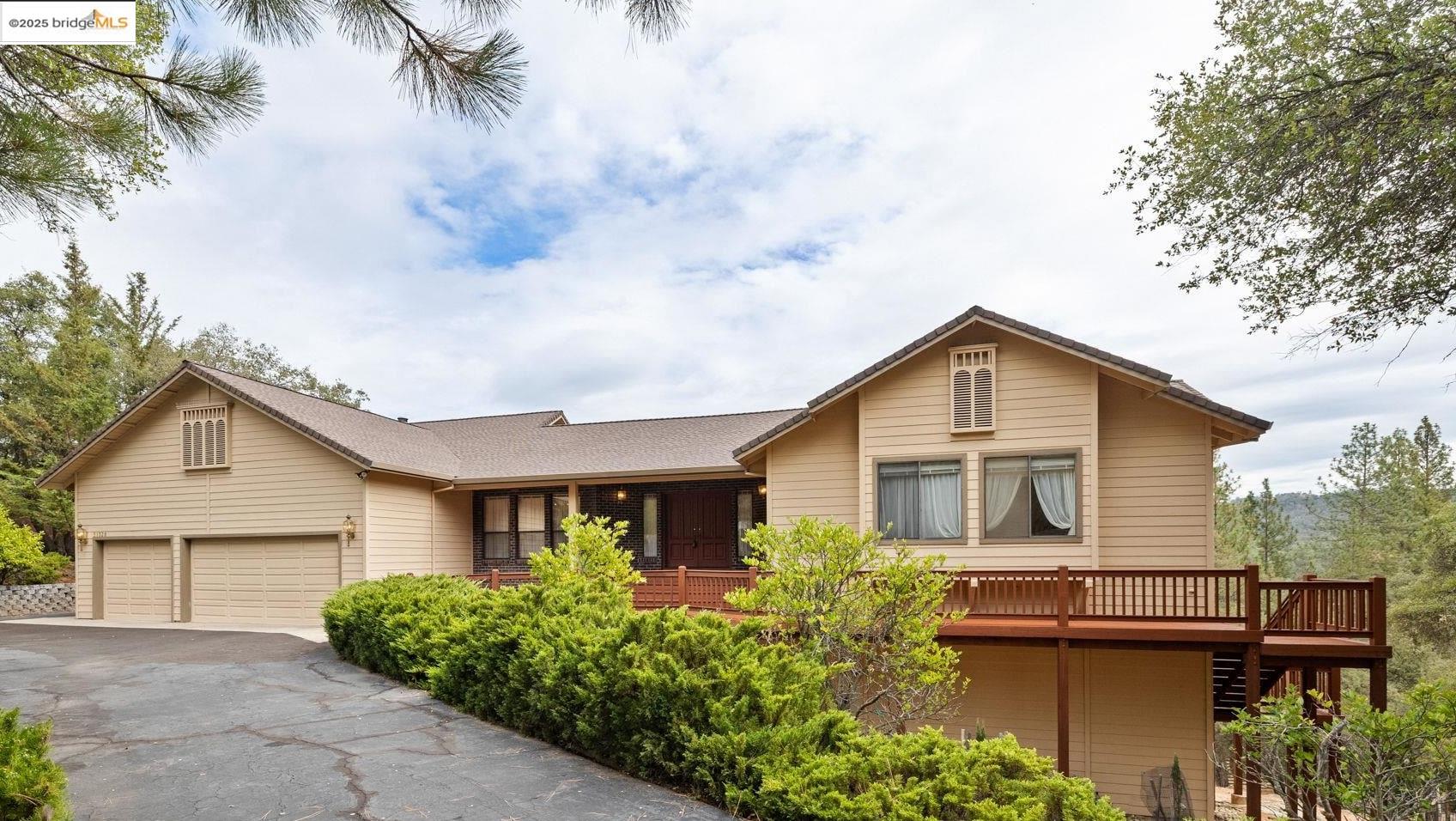 View of front facade with driveway and a wooden deck