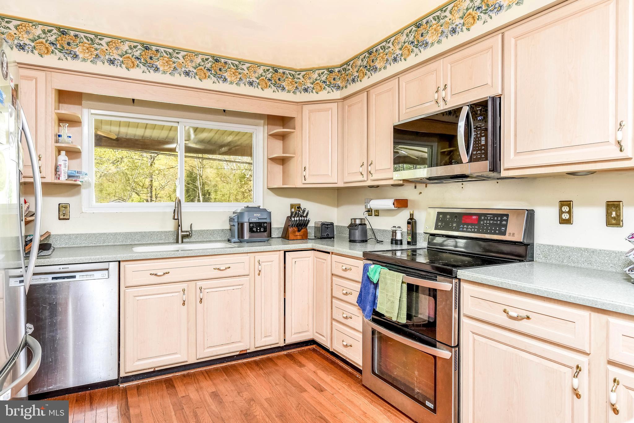 7809 Lake Drive Manassas, VA 20111 - Photo 16 of 44 a kitchen with stainless steel appliances granite countertop a stove top oven a sink dishwasher and white cabinets with wooden floor