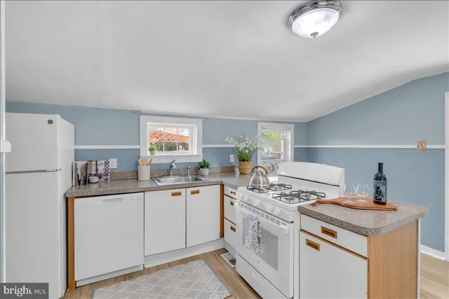 a kitchen with a sink a stove a refrigerator and white cabinets