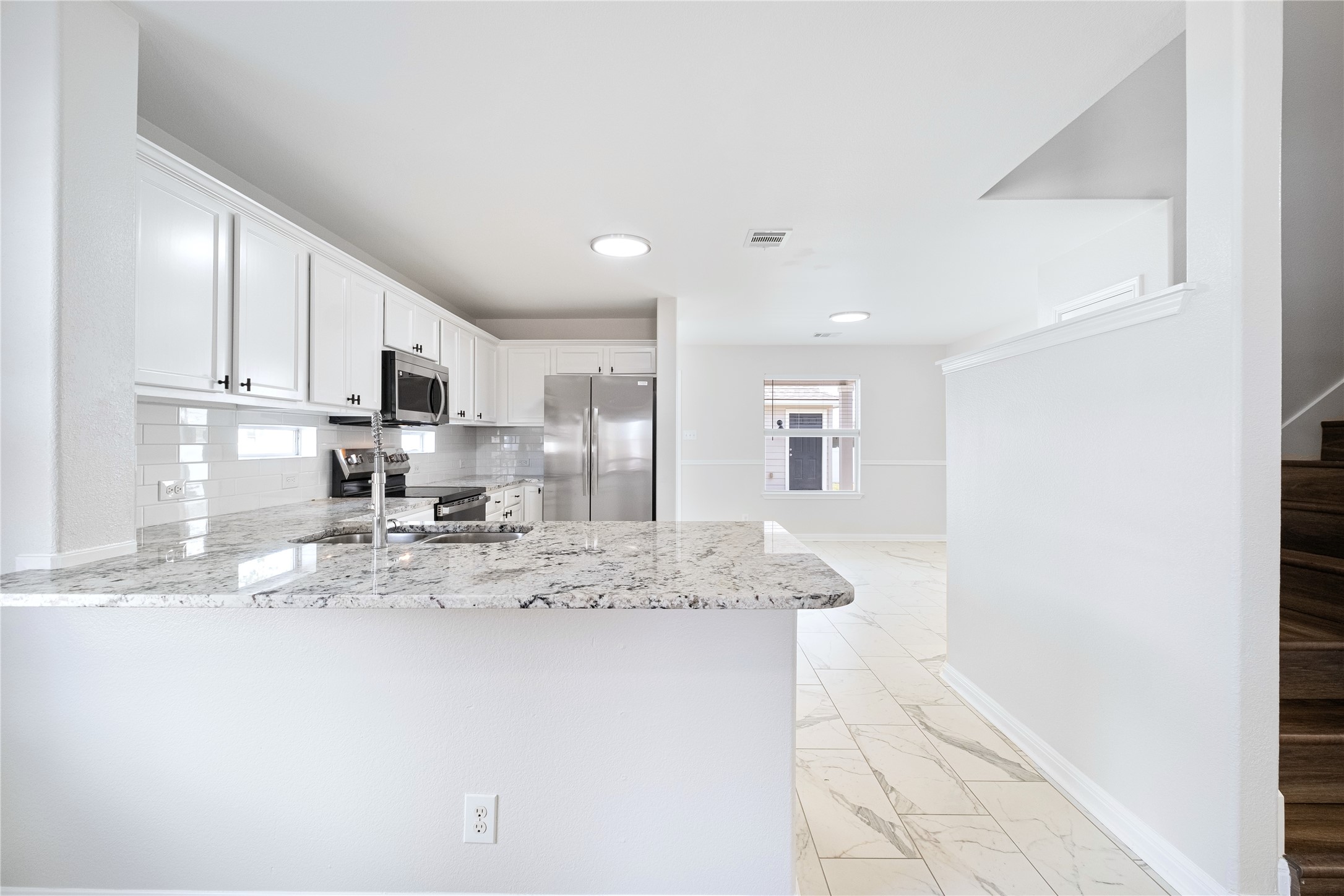 1400 Portchester Castle Path Pflugerville, TX 78660 - Photo 13 of 40 Kitchen with light stone counters, white cabinets, stainless steel appliances, a peninsula, and decorative backsplash