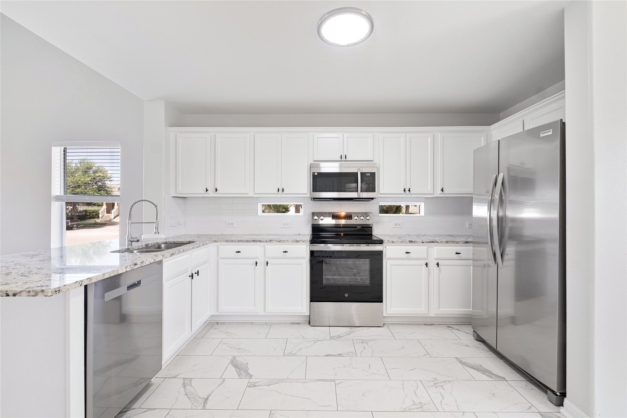 1400 Portchester Castle Path Pflugerville, TX 78660 - Photo 14 of 40 Kitchen with stainless steel appliances, light marble finish floors, and white cabinetry