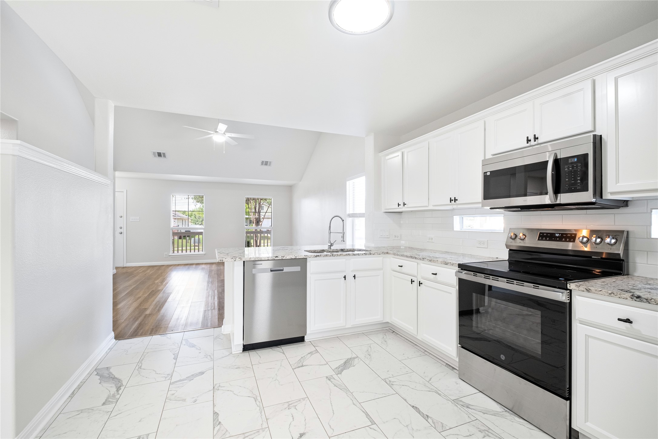 1400 Portchester Castle Path Pflugerville, TX 78660 - Photo 15 of 40 Kitchen with stainless steel appliances, light marble finish flooring, lofted ceiling, and white cabinetry